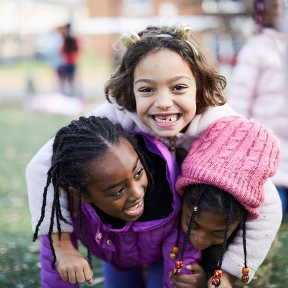 elementary student friends hug on the playground