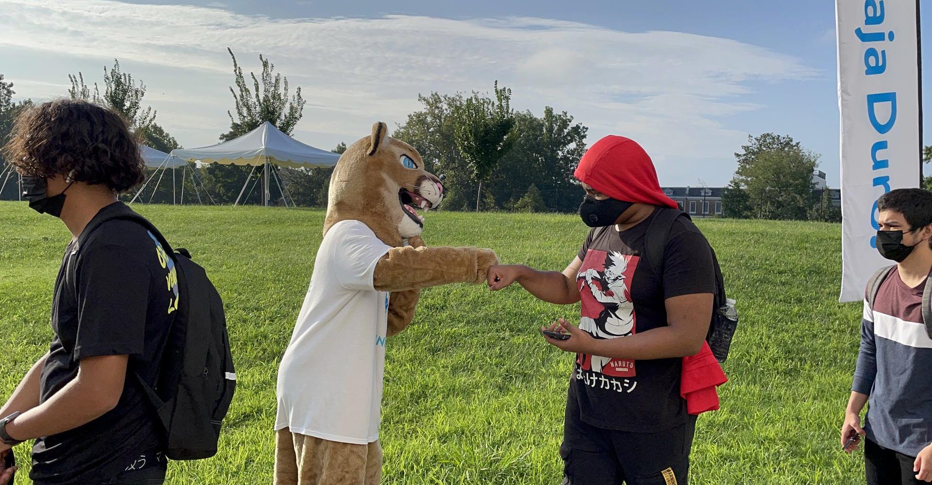 Image of a mountain lion mascot bumping fists with a high school student on the first day of school.